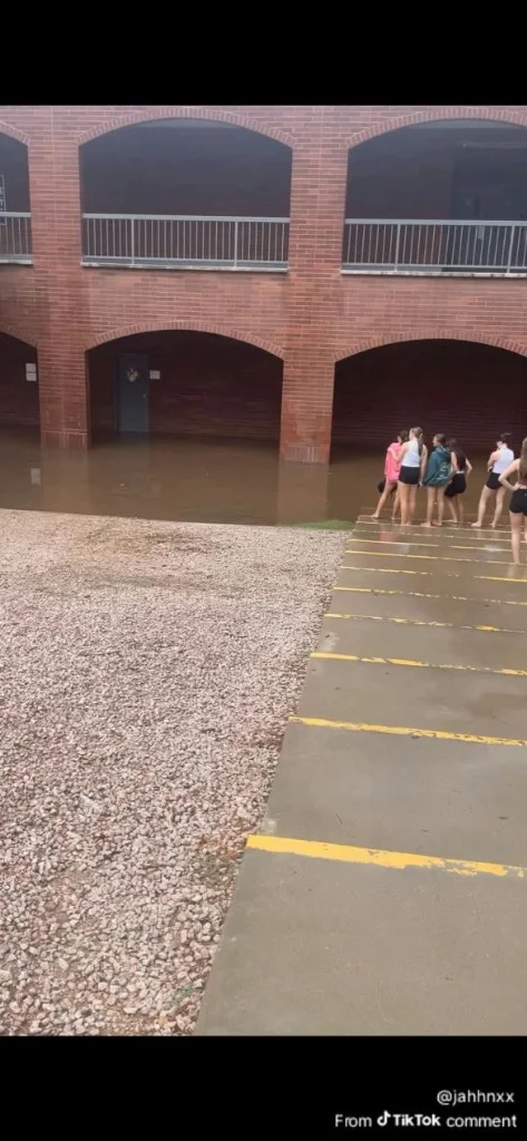Red Mountain High School students observing deep floodwater ponding outside the arched ground-level classroom building